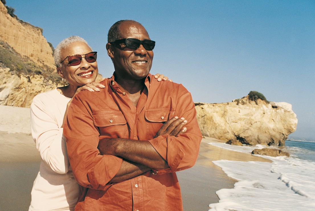 Retired Couple at Waters Edge, Woman Standing Behind Man With her Hands on his Shoulders