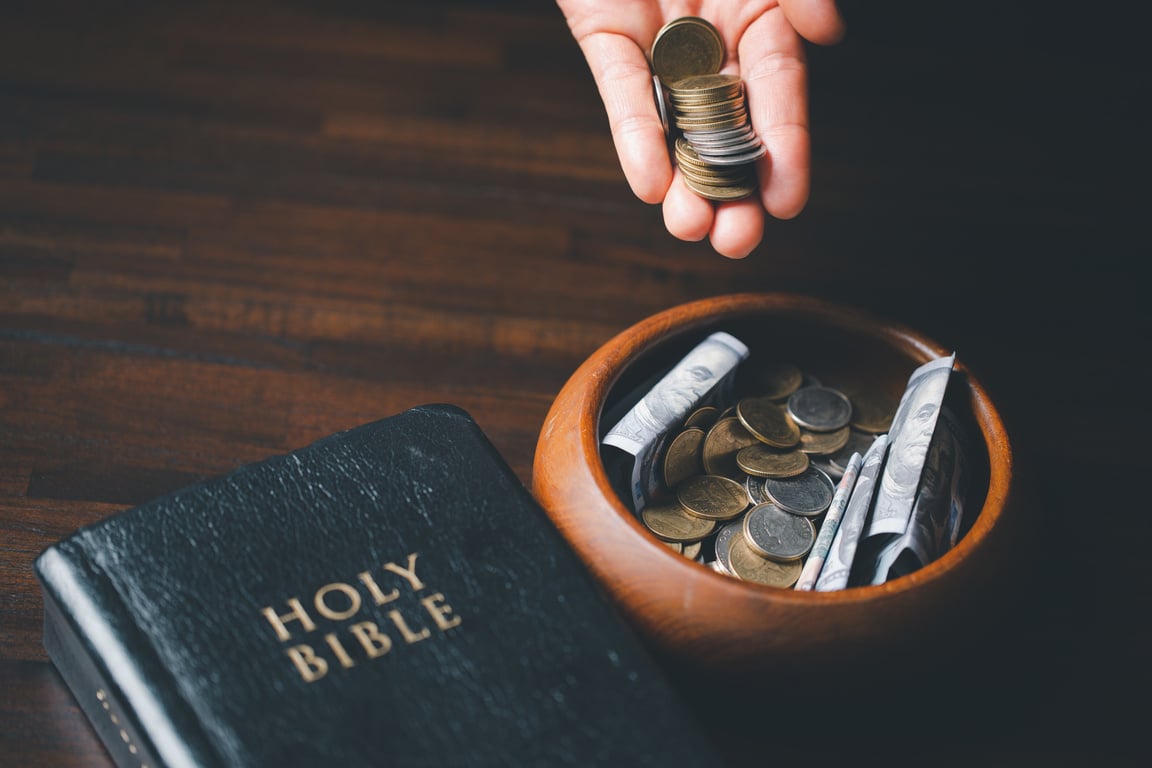 One tenth or tithe is basis on which Bible teaches us to give one tenth of first fruit to God. coins with Holy Bible. Biblical concept of Christian offering, generosity, and giving tithes in church.